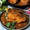 stuffed poblano pepper with red sauce on black plate