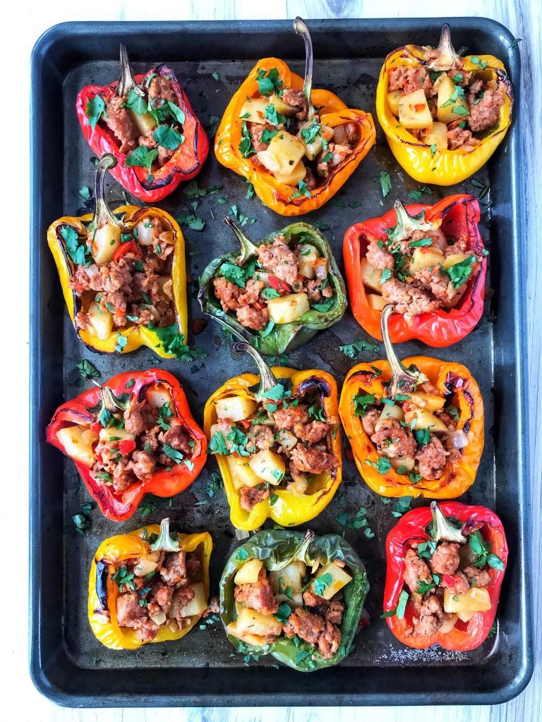 Bell peppers stuffed with chorizo con papas on a cookie sheet.