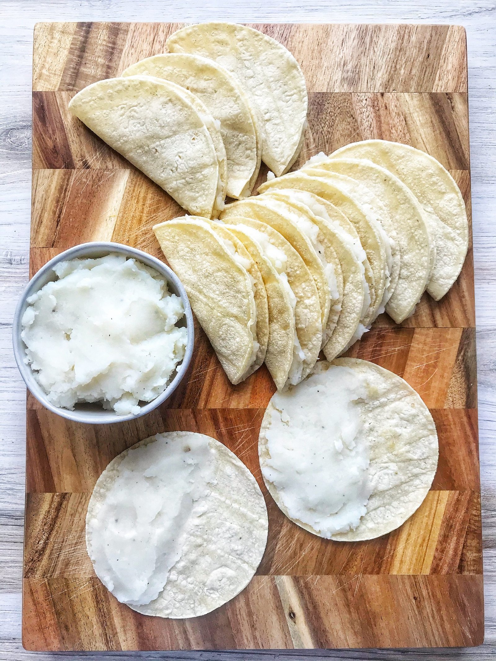 White corn tortillas filled with mashed potato. Open potato tacos and folded potato tacos.