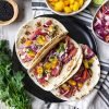 Ahi tuna tacos with slaw and mango on black plate