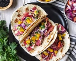 Ahi tuna tacos with slaw and mango on black plate