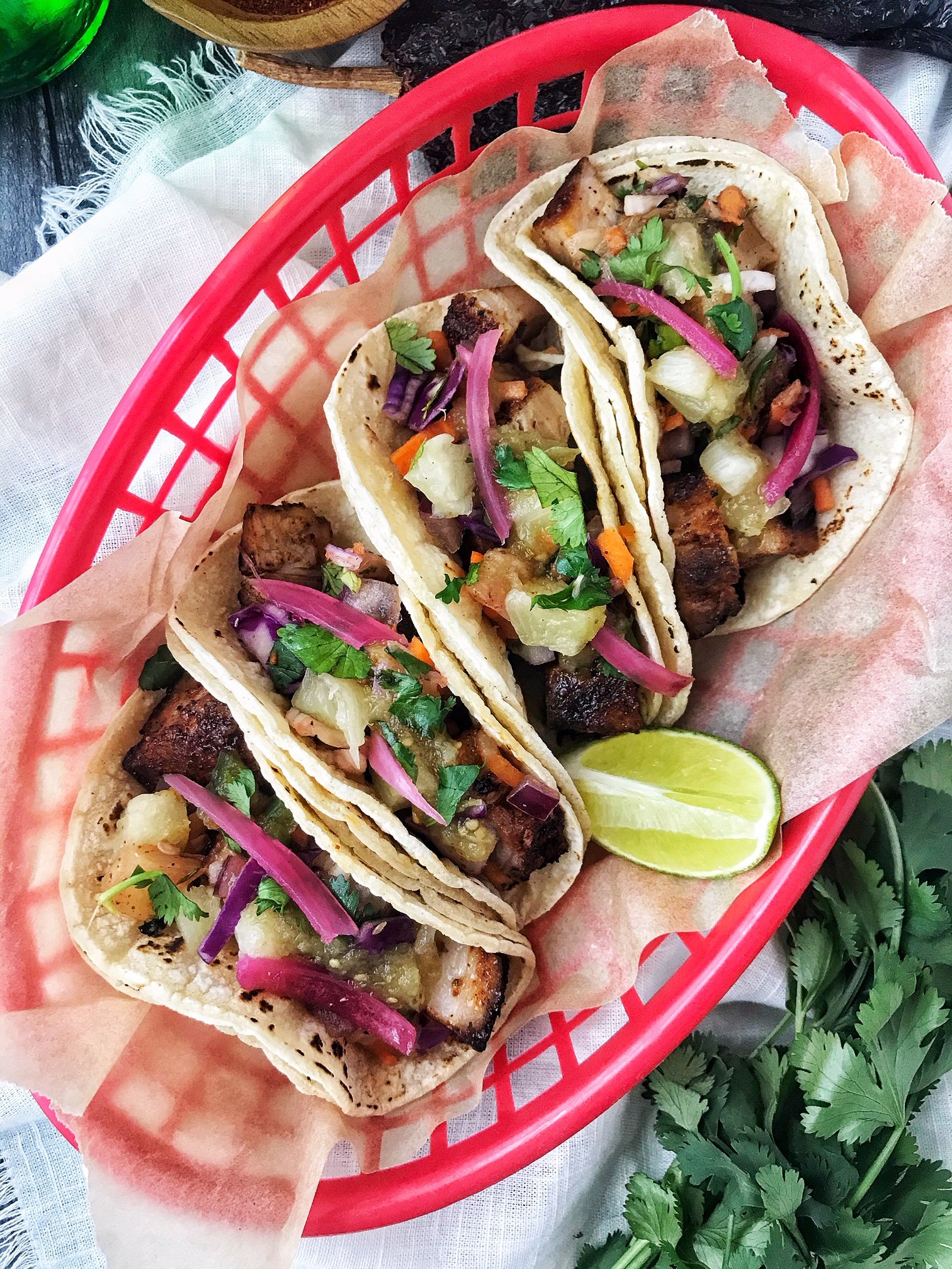 Pork belly tacos in red basket. Pineapple slaw, red onion, and lime.
