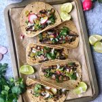Mushroom Asada Tacos with onions, cilantro, salsa and radishes. Taco on baking sheet pan.