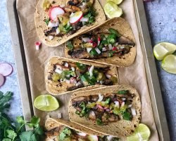 Mushroom Asada Tacos with onions, cilantro, salsa and radishes. Taco on baking sheet pan.