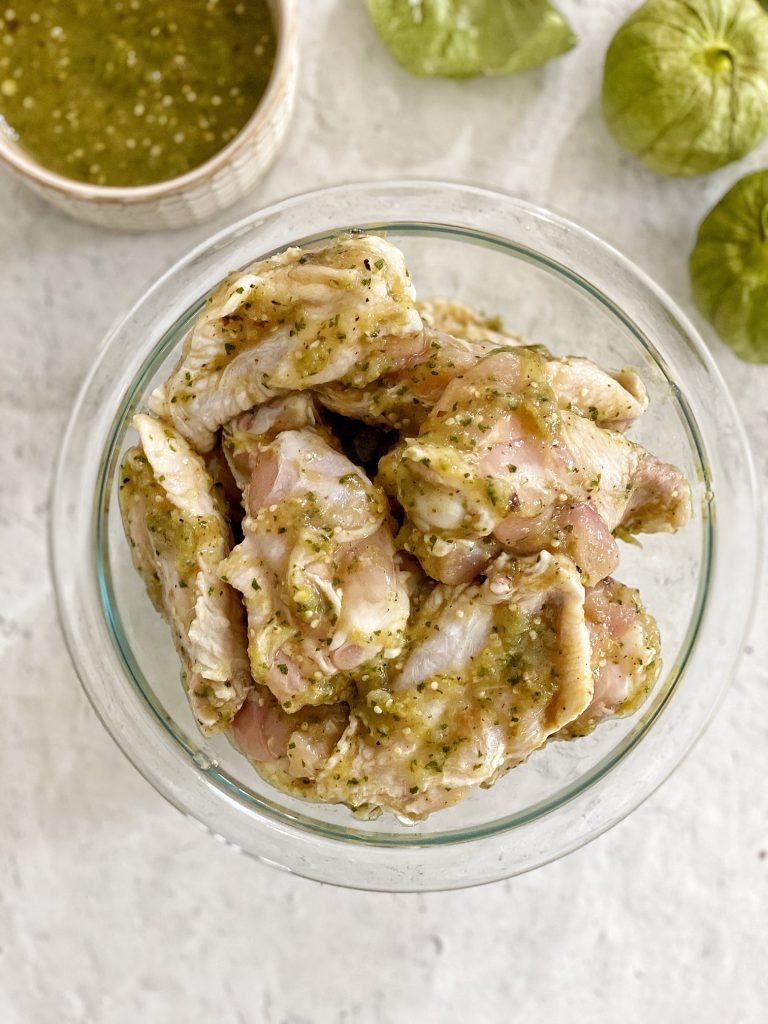 Chicken wings marinating in salsa verde. Salsa verde and tomatillos on the side. 