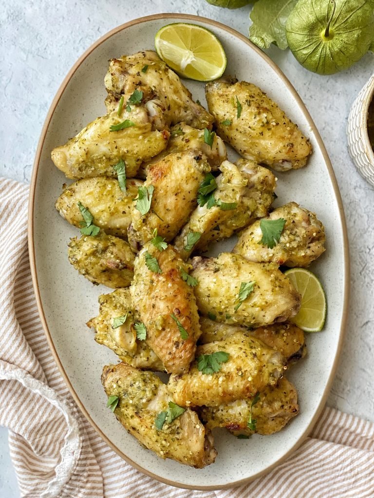 Platter of salsa verde wings with cilantro prinkled on top and a lime wedge.
