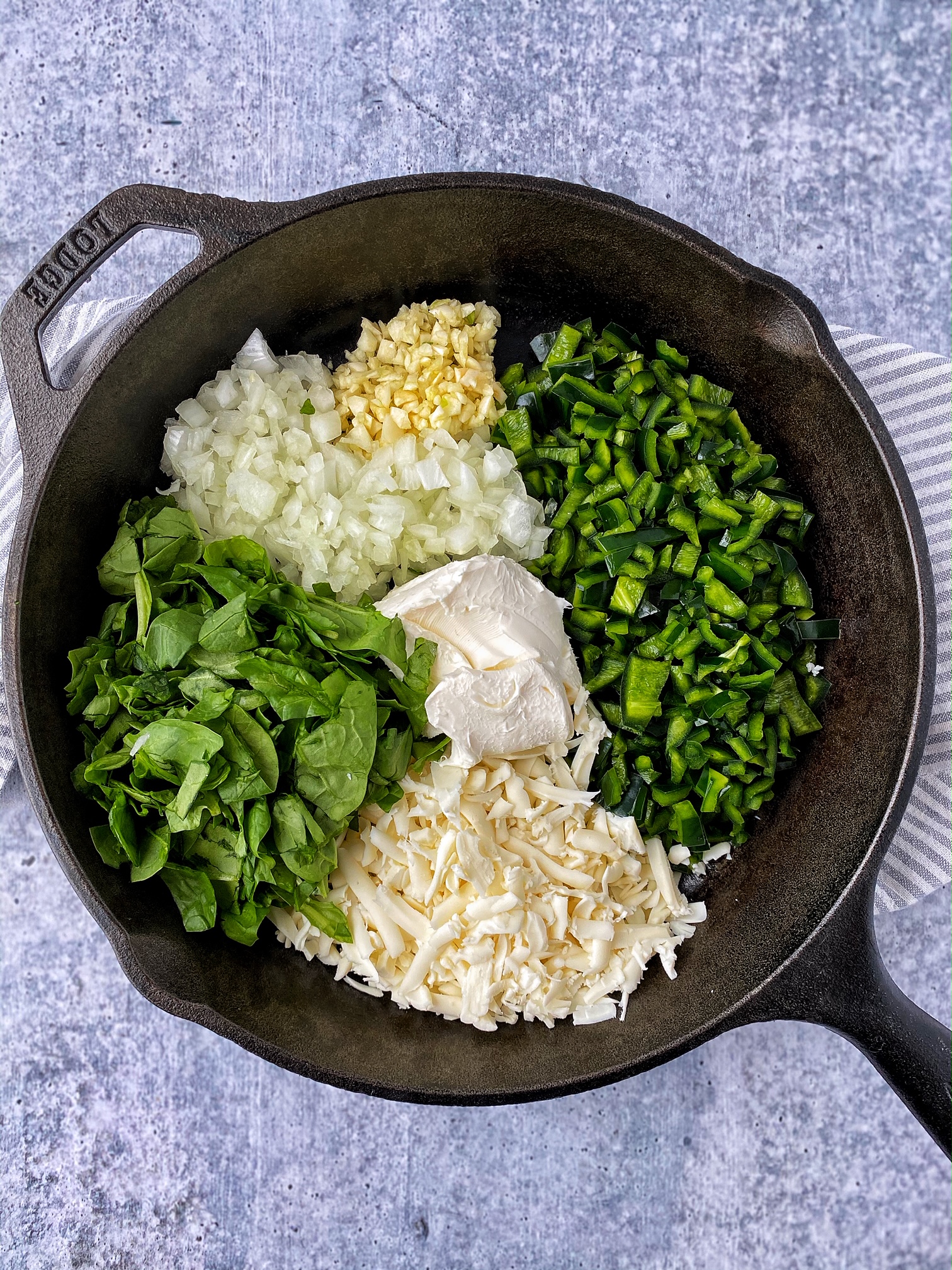 Cast iron with chopped peppers, onions, garlic, spinach, shredded cheese, and cream cheese