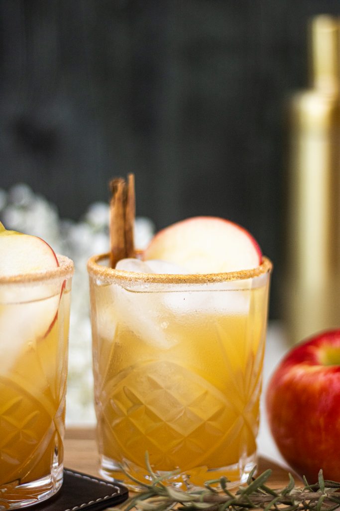 Apple  cider margarita with apple slice and cinnamon stick garnish. Apple on side
