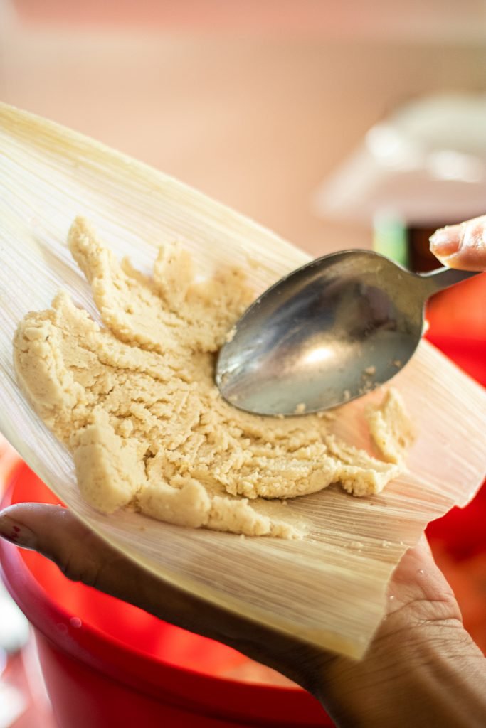 Masa being spread with a spoon onto corn husk