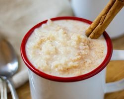 White mugs with red rim filled with arroz con leche