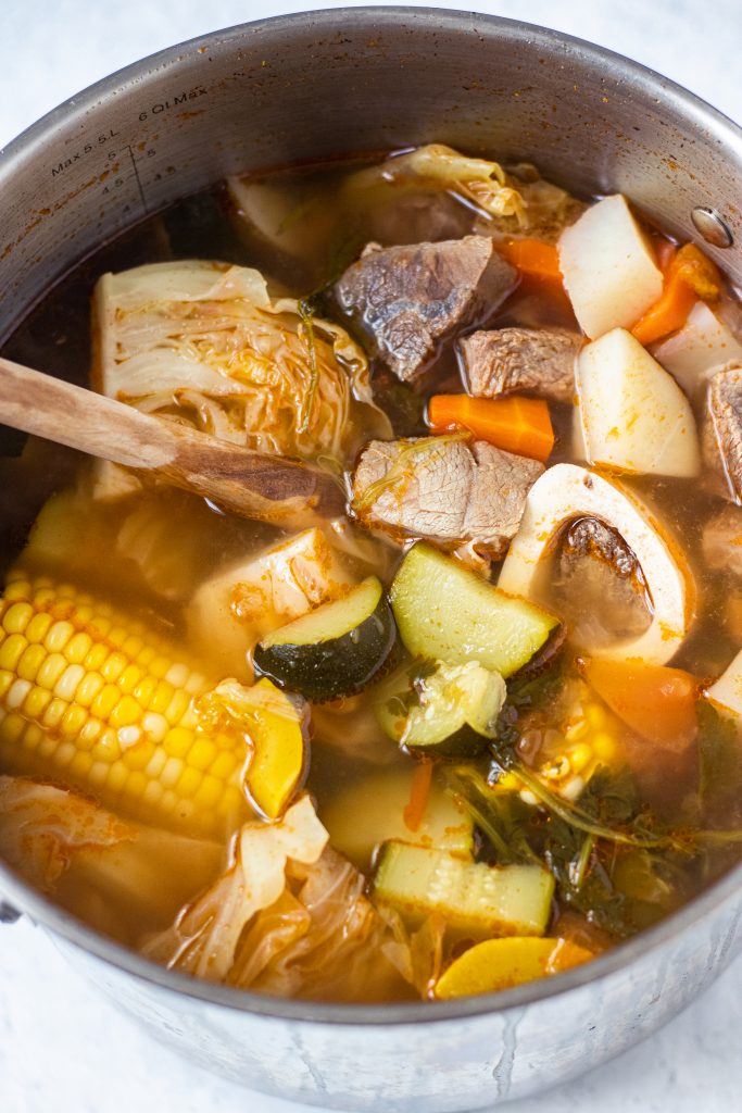 Large pot with caldo de res with corn, zucchini, carrots, cabbage, and beef. 