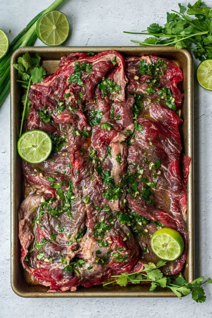 Arracher, skirt steak, with marinade. Cilantro and lime garnish all on small sheet pan.