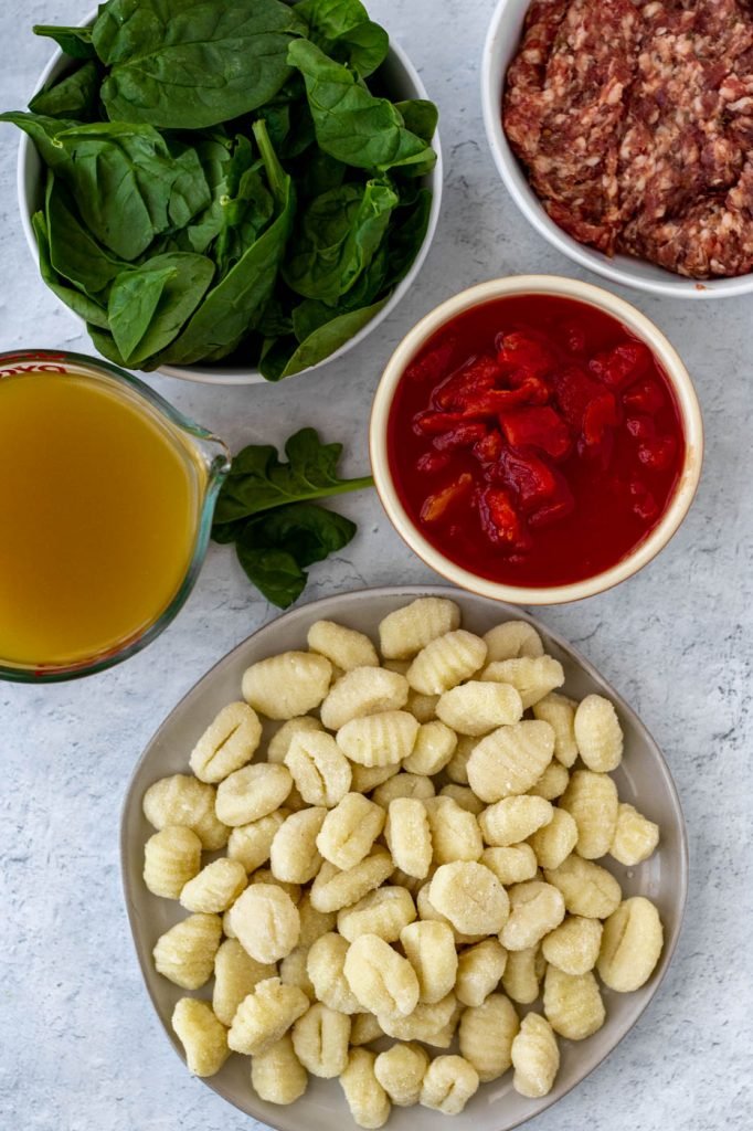Soup ingredients. Gnocchi, canned tomatoes, spinach, broth, sausage.