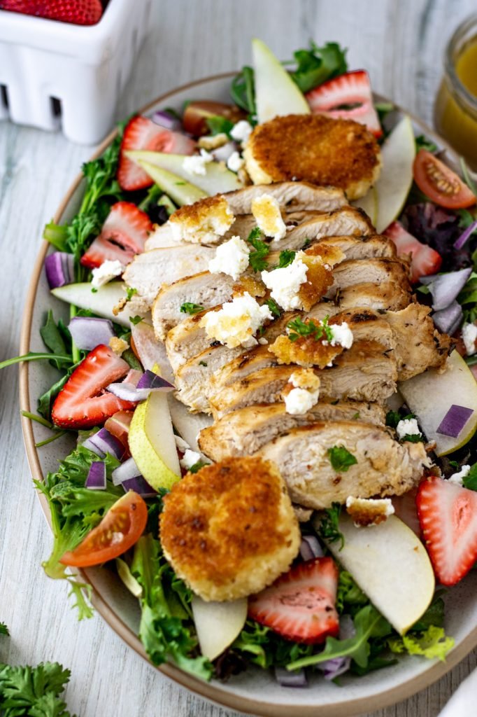 Salad platter with greens, strawberries, pears, and grilled chicken. Topped with fried goat cheese medallions and red wine vinaigrette.
